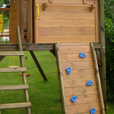 KASO Kletterwand K1 aus Holz mit blauen Klettersteinen an einem Spielturm im Garten