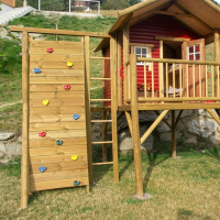 KASO Kletterwand K3 Rundstamm Aus Kiefer KDI mit bunten Klettersteinen und seitlicher Kletterleiter an einem Stelzenhaus im Garten
