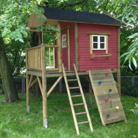 Schweden-Stelzenhaus aus Holz in Rot mit Leiter, Kletterwand und Balkon im grünen Garten.