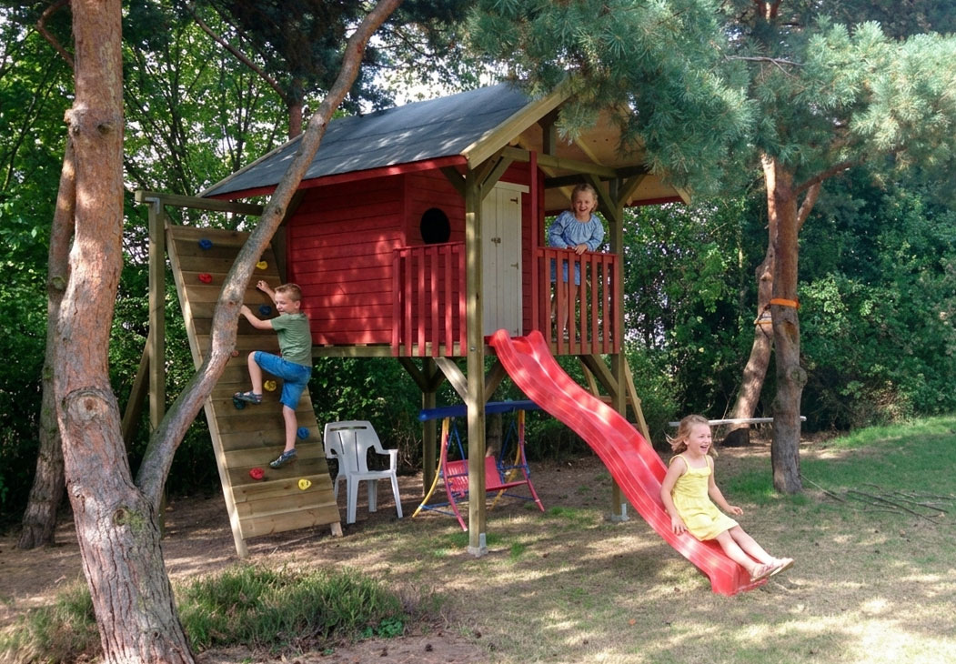 Spielende Kinder am Stelzenhaus Maxx XL-A2 mit Wellenrutsche und Kletterwand im Garten